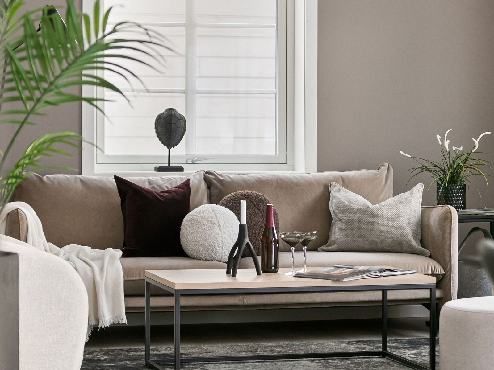 Wohnraum mit Sofa, Couchtisch und Pflanzen in ruhigen Beigetönen